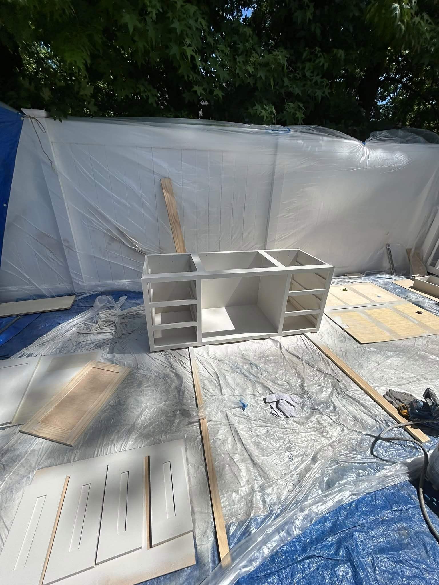 Cabinet finishing work with protective sheeting covering the surrounding work area